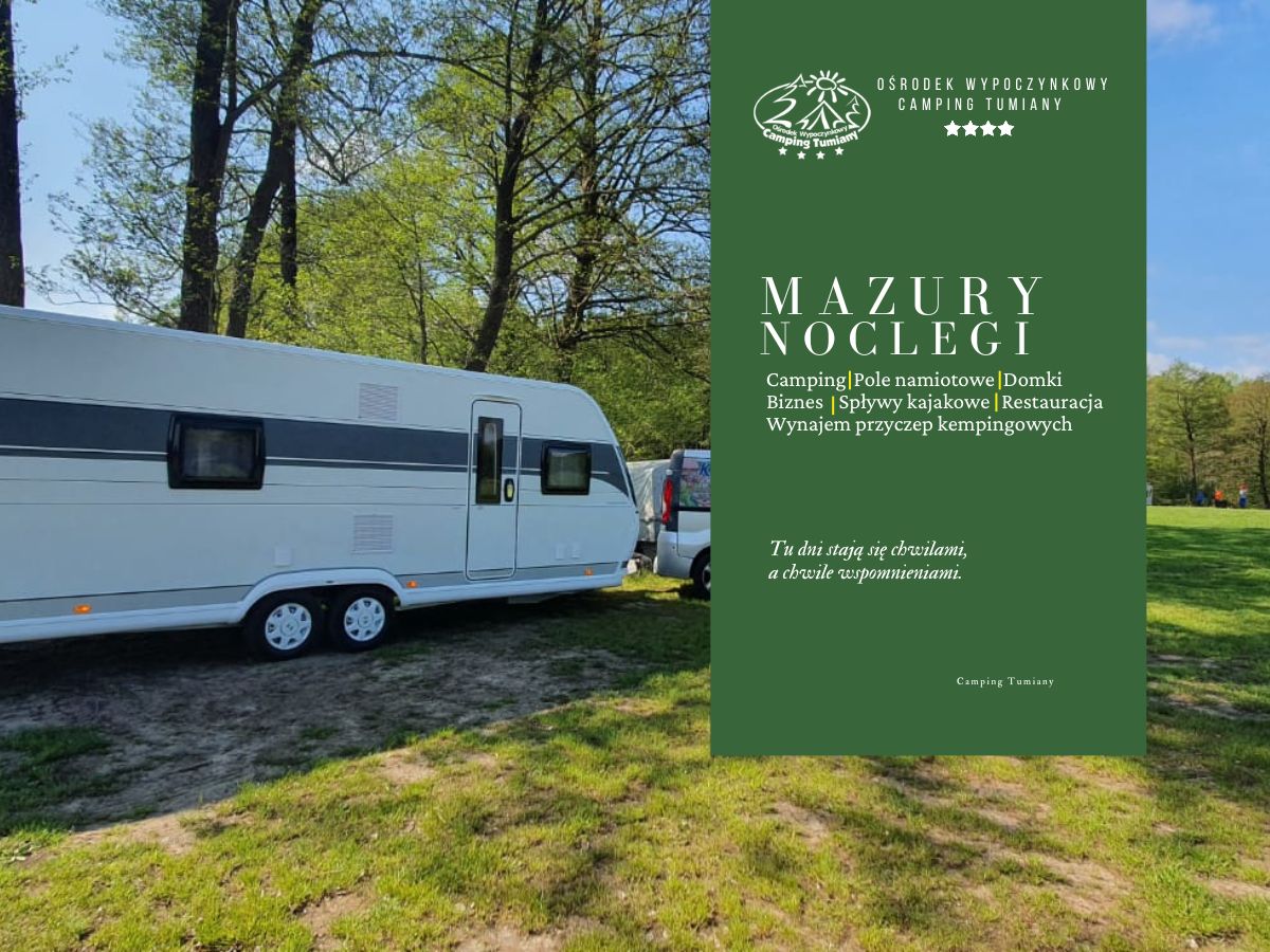 Przyczepa kempingowa zaparkowana na trawie, obok znak reklamujący wypożyczalnię przyczep kempingowych.